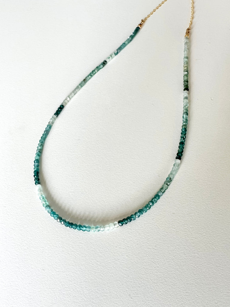 Green ombre grandidierite gemstone necklace featuring a gold clasp on a white background.