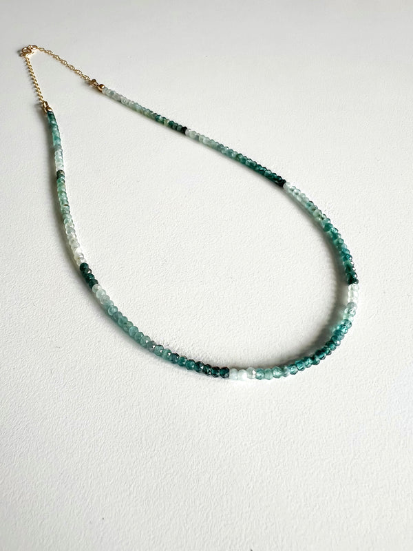 Green ombre grandidierite gemstone necklace featuring a gold clasp on a white background.