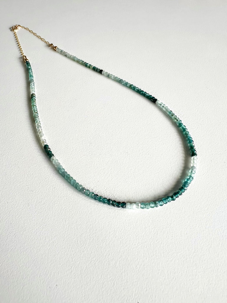 Green ombre grandidierite gemstone necklace featuring a gold clasp on a white background.