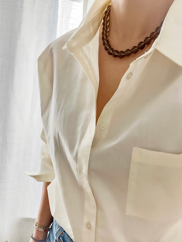 12 mm round smoky quartz strand necklace worn by a model over a white button-up shirt paired with jeans, showing the necklace from a different angle